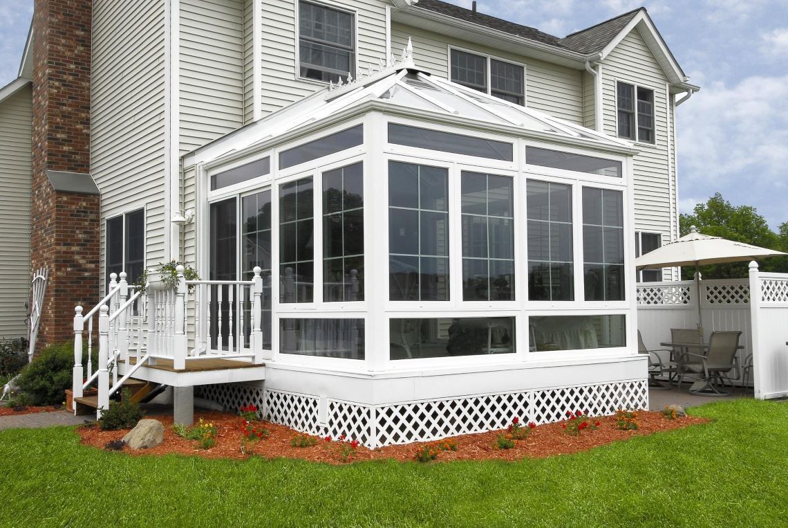 A white house with a sunroom attached to it.