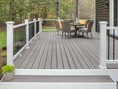 A deck with a table and chairs on it and a white railing.