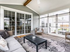 A living room with a couch, table, chairs, and sliding glass doors.