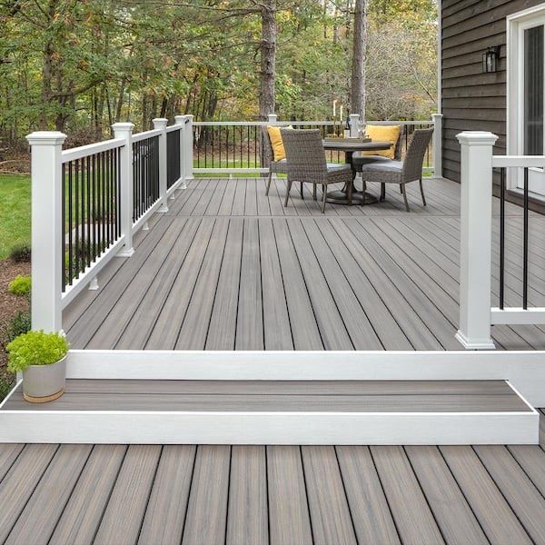 A deck with a table and chairs on it and a white railing.