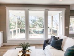 A living room with a couch, table, and lots of windows.