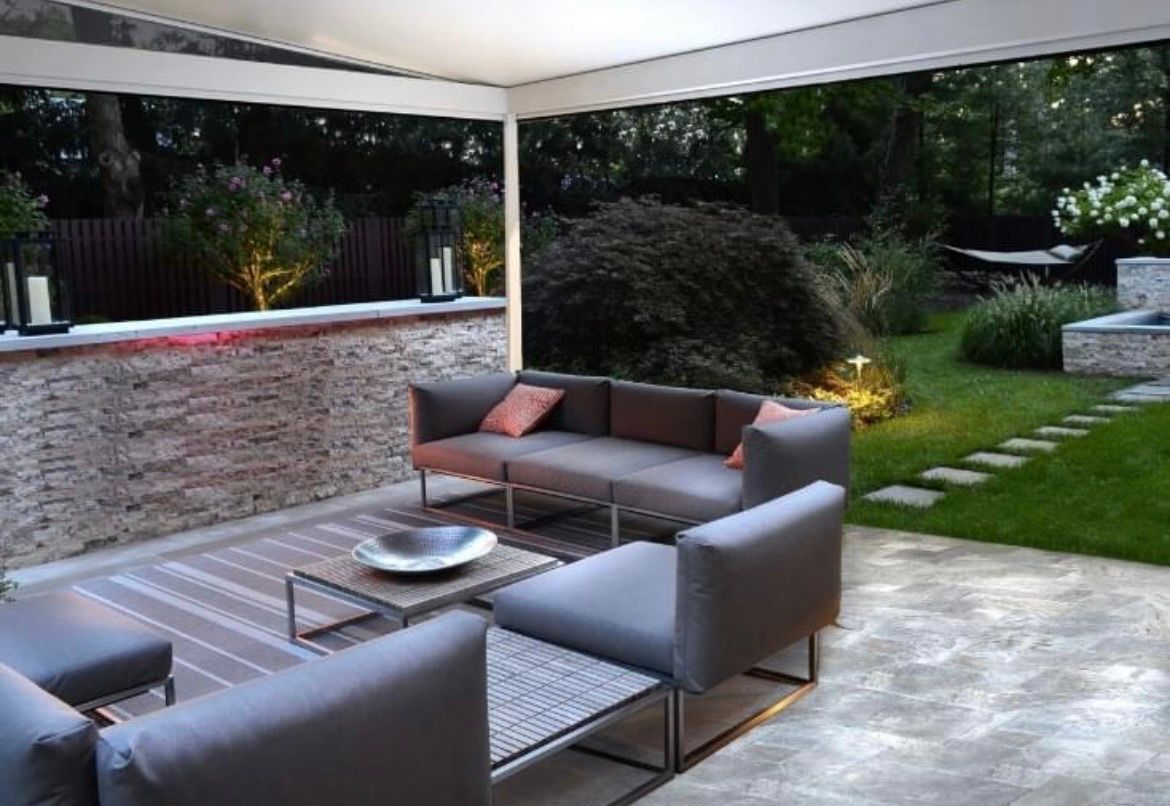 A patio with a couch and chairs under a canopy