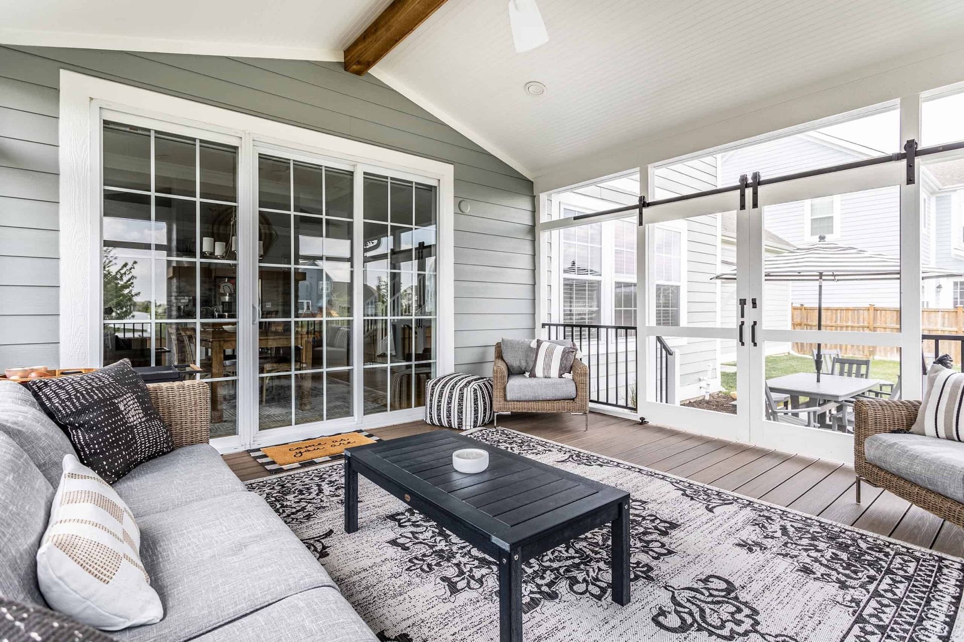 A screened-in porch with a couch, chairs, and a coffee table.