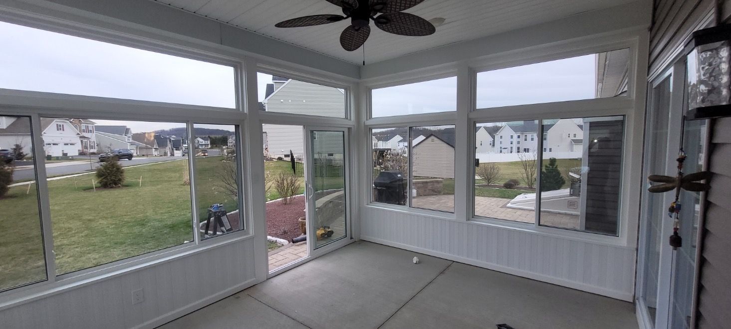 A screened in porch with a lot of windows and a ceiling fan.