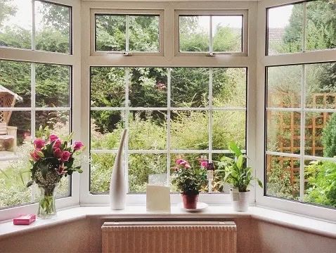 A window with flowers and vases on the window sill
