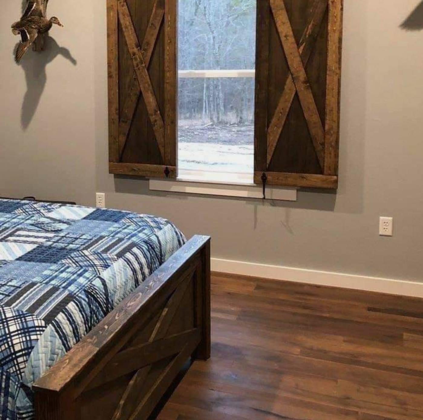 A bedroom with a bed and a window with wooden shutters