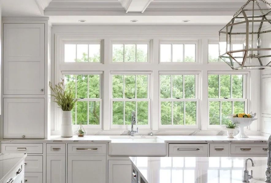 A kitchen with white cabinets, a sink, and a lot of windows.