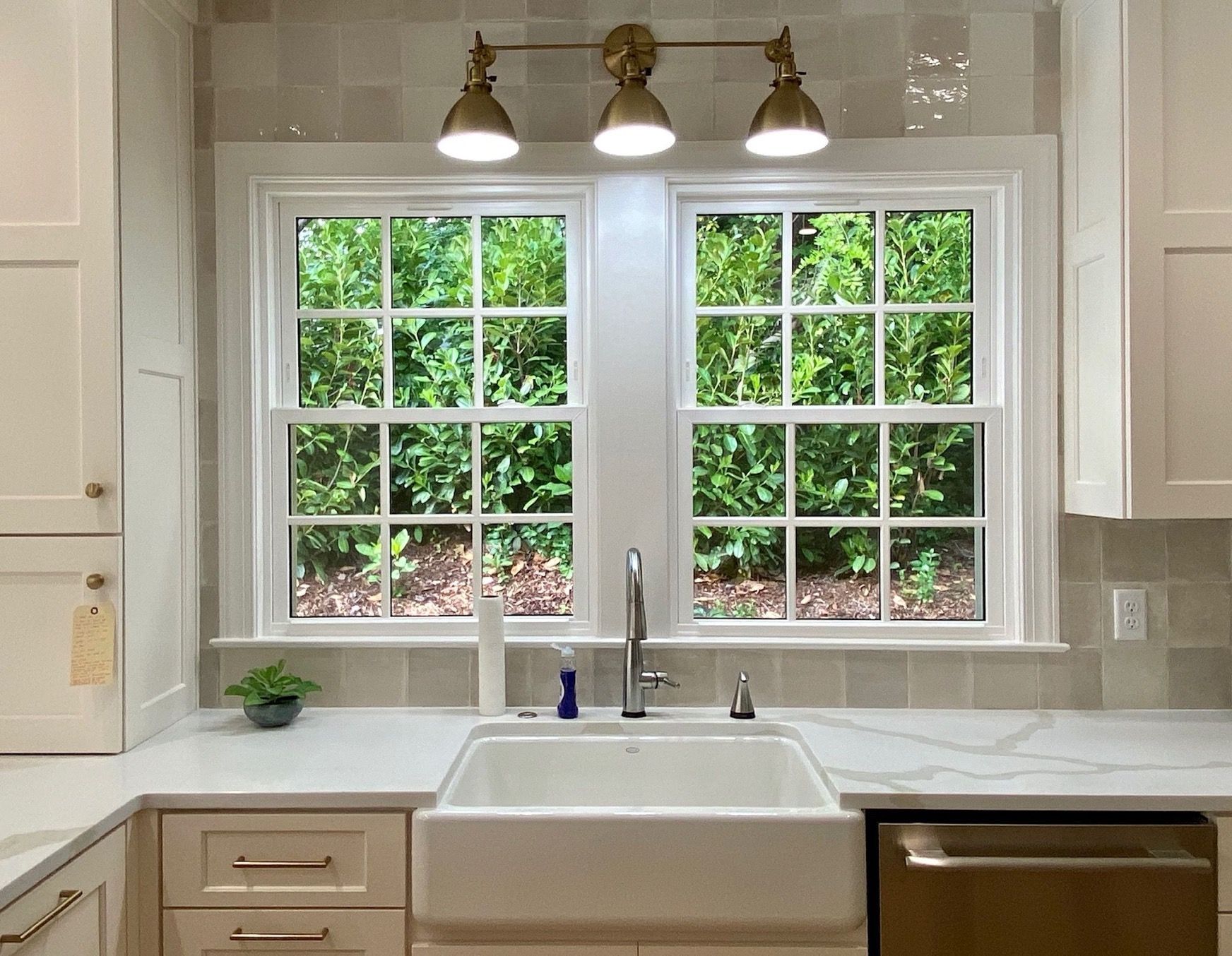 A kitchen with a white sink and two windows