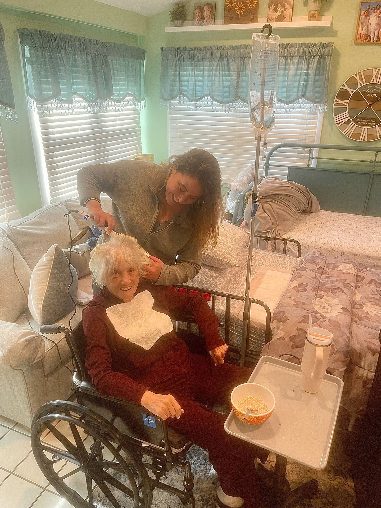 A woman is cutting the hair of an elderly woman in a wheelchair.