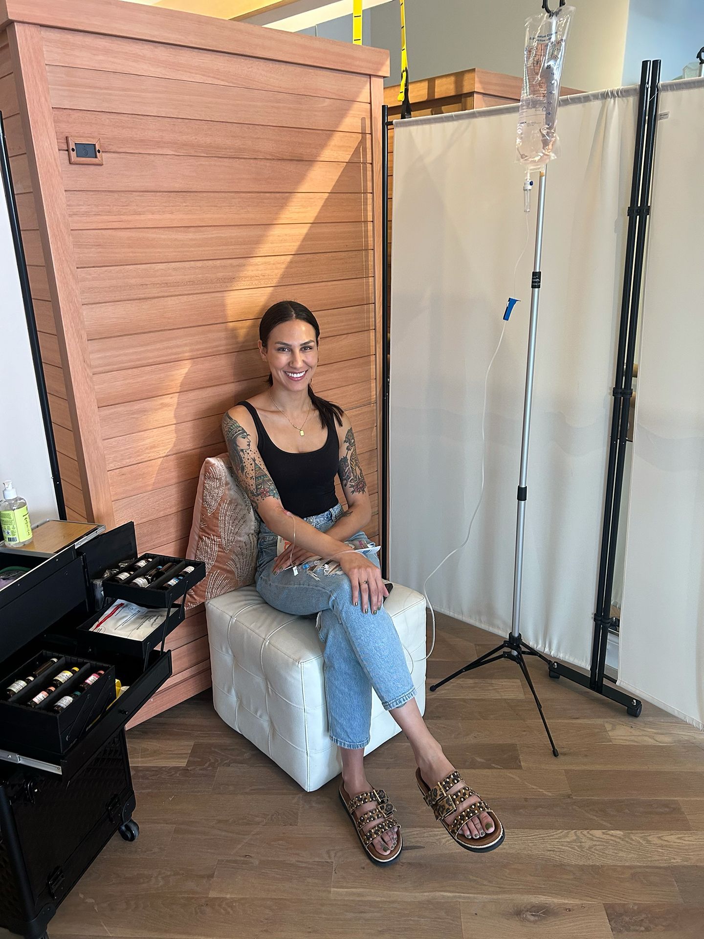 A woman is sitting in a chair with an iv in her hand.