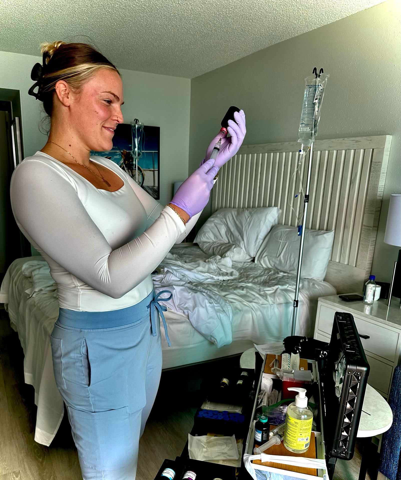 A woman wearing purple gloves is standing in front of a bed.
