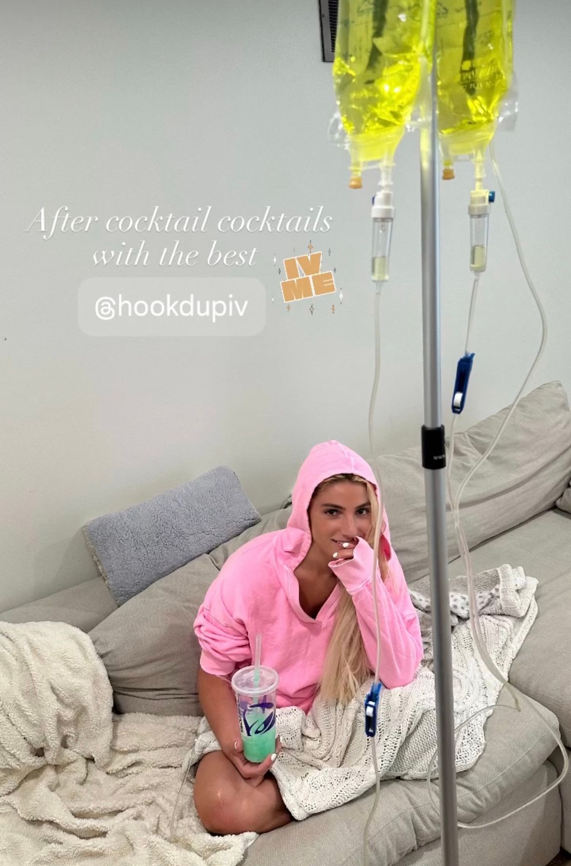 A woman is sitting on a couch with an iv in her hand.
