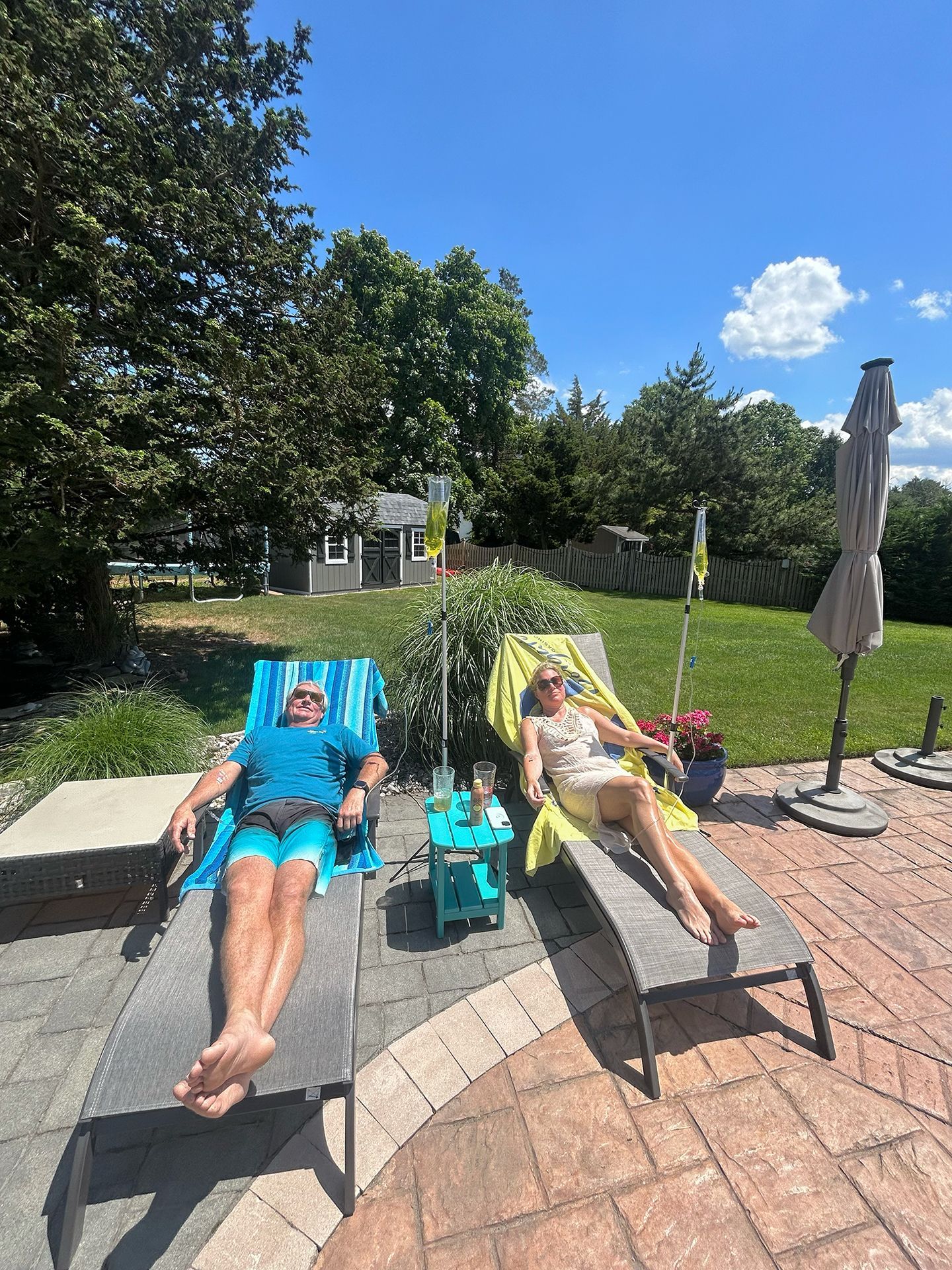 Two people are sitting on lounge chairs on a patio.