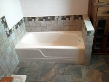 A bathtub is sitting in a bathroom next to a tiled wall.