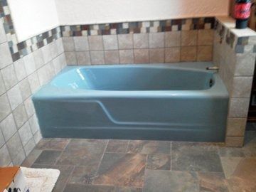 A blue bathtub is sitting in a bathroom next to a tiled wall.