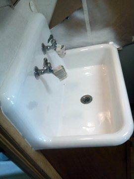 A white sink with two faucets and a drain in a bathroom.