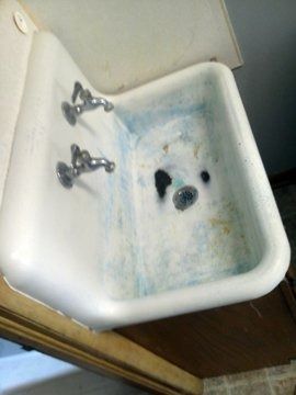 A white sink with three faucets is sitting on a counter in a bathroom.