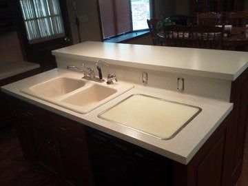 A kitchen with two sinks and a cutting board on the counter.