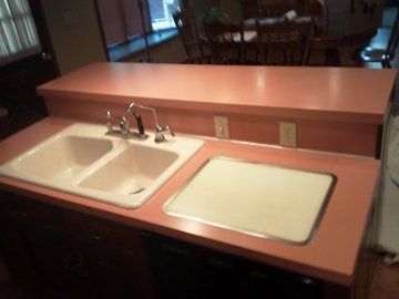 A kitchen counter with two sinks and a cutting board