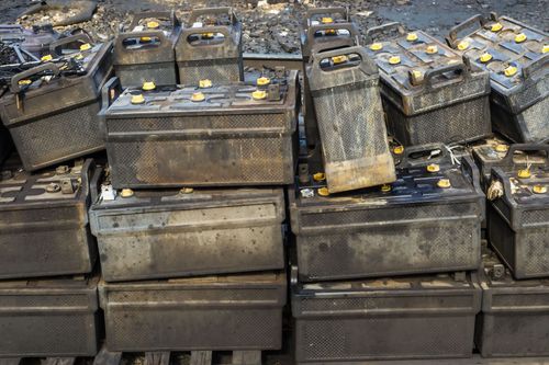 Stacks of black plastic crates filled with small yellow-lidded containers in an industrial warehouse