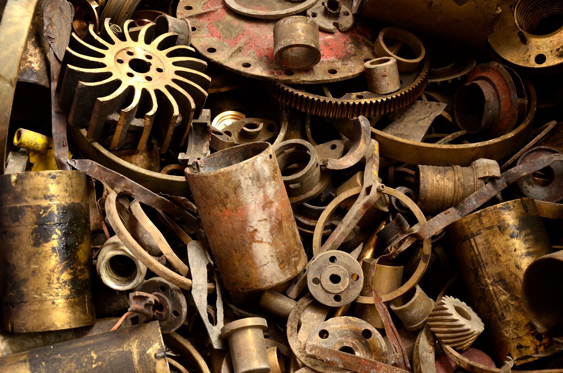 Pile of rusted scrap metal parts and gears in brown and gold tones