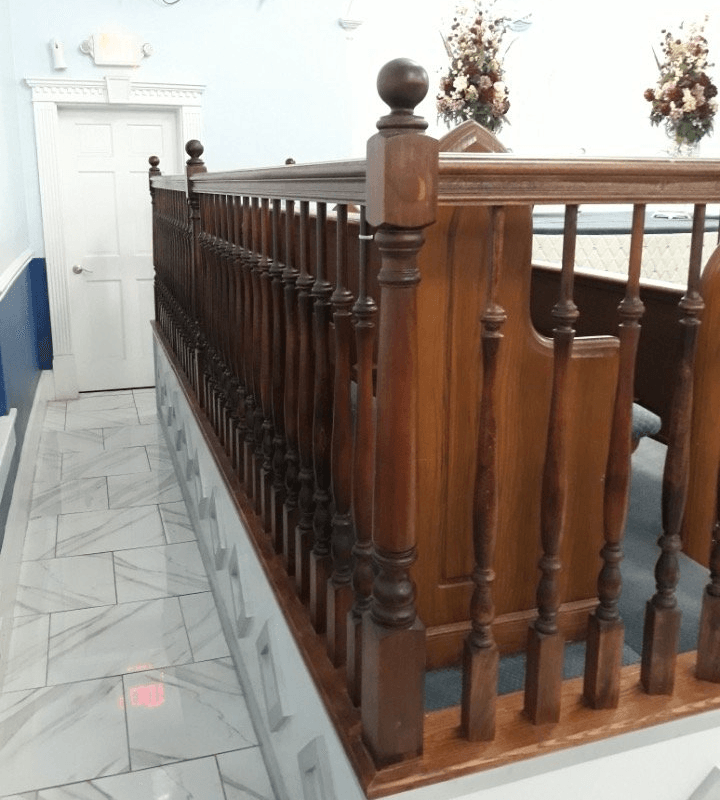 Wooden banister and pews inside a building, possibly a church.