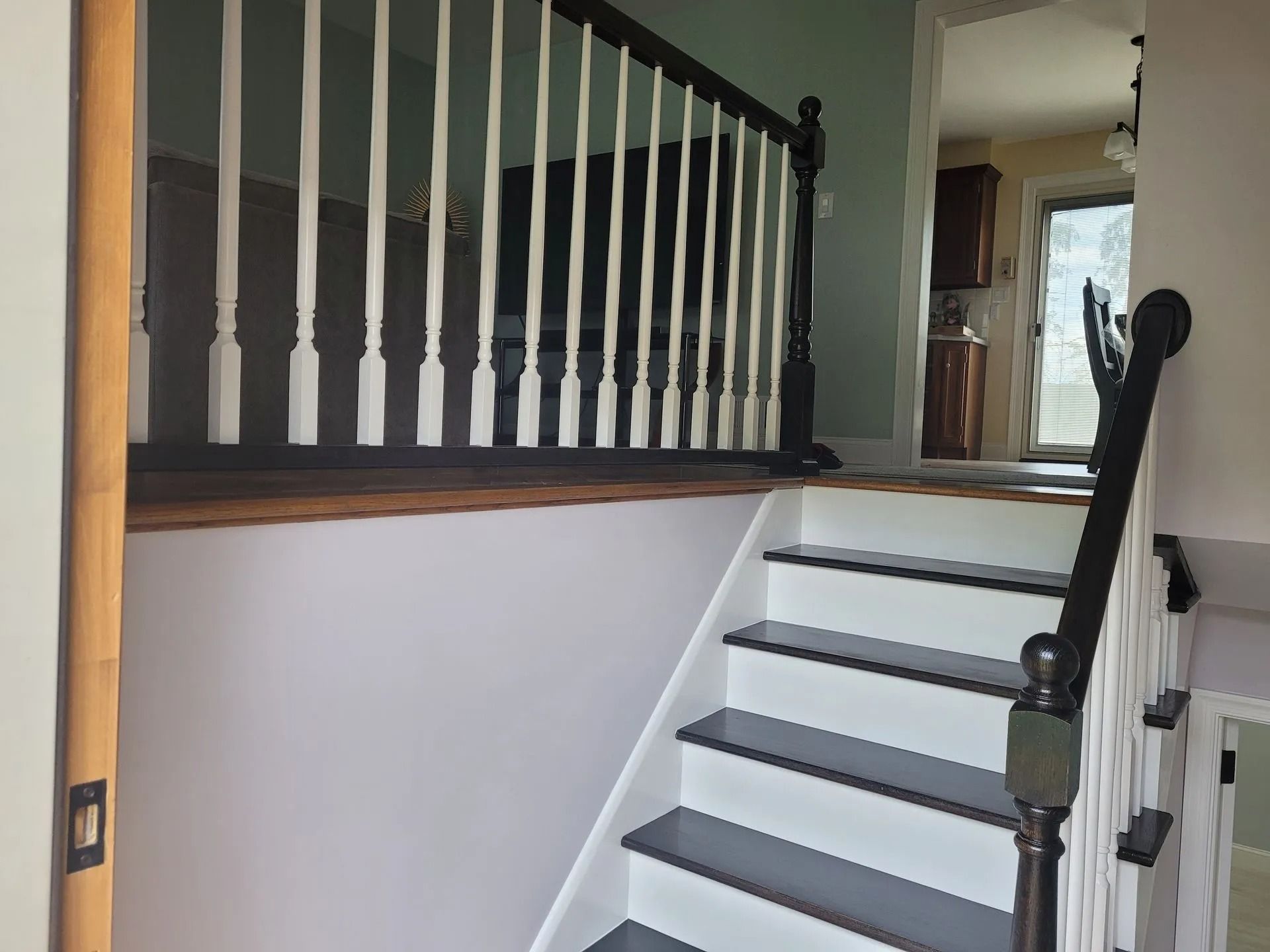Staircase with white risers and dark treads, leading to a landing with a dark railing.