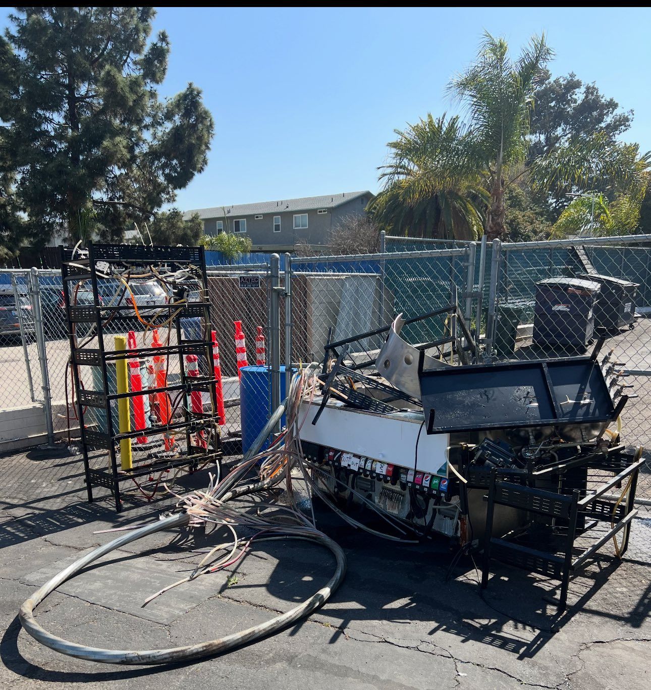 Damaged generator and equipment outside, likely from a fire. Burned and twisted metal, with caution cones and a fence.