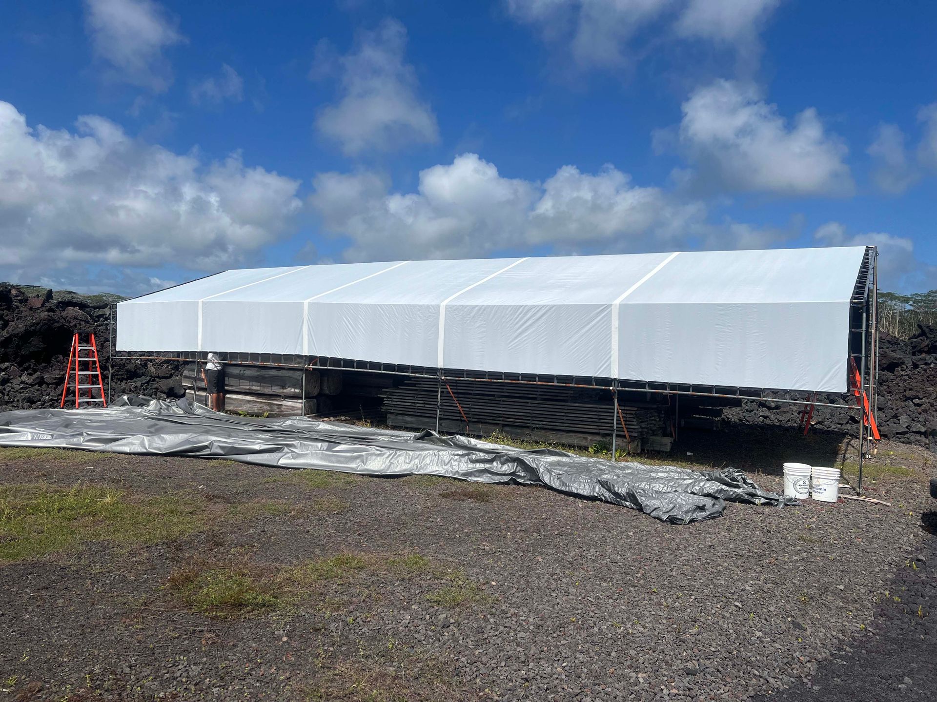 A large white tent is sitting on top of a dirt field.