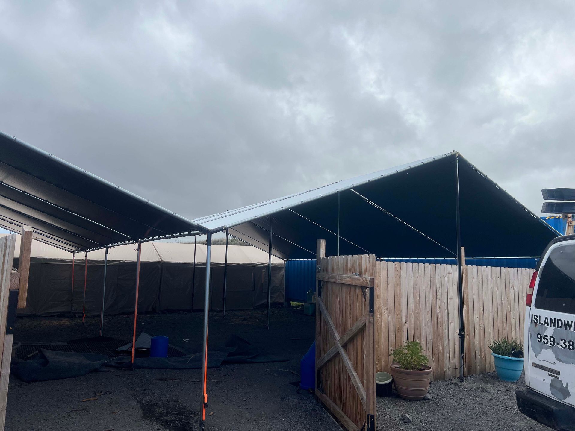 A white van is parked in front of a large tent