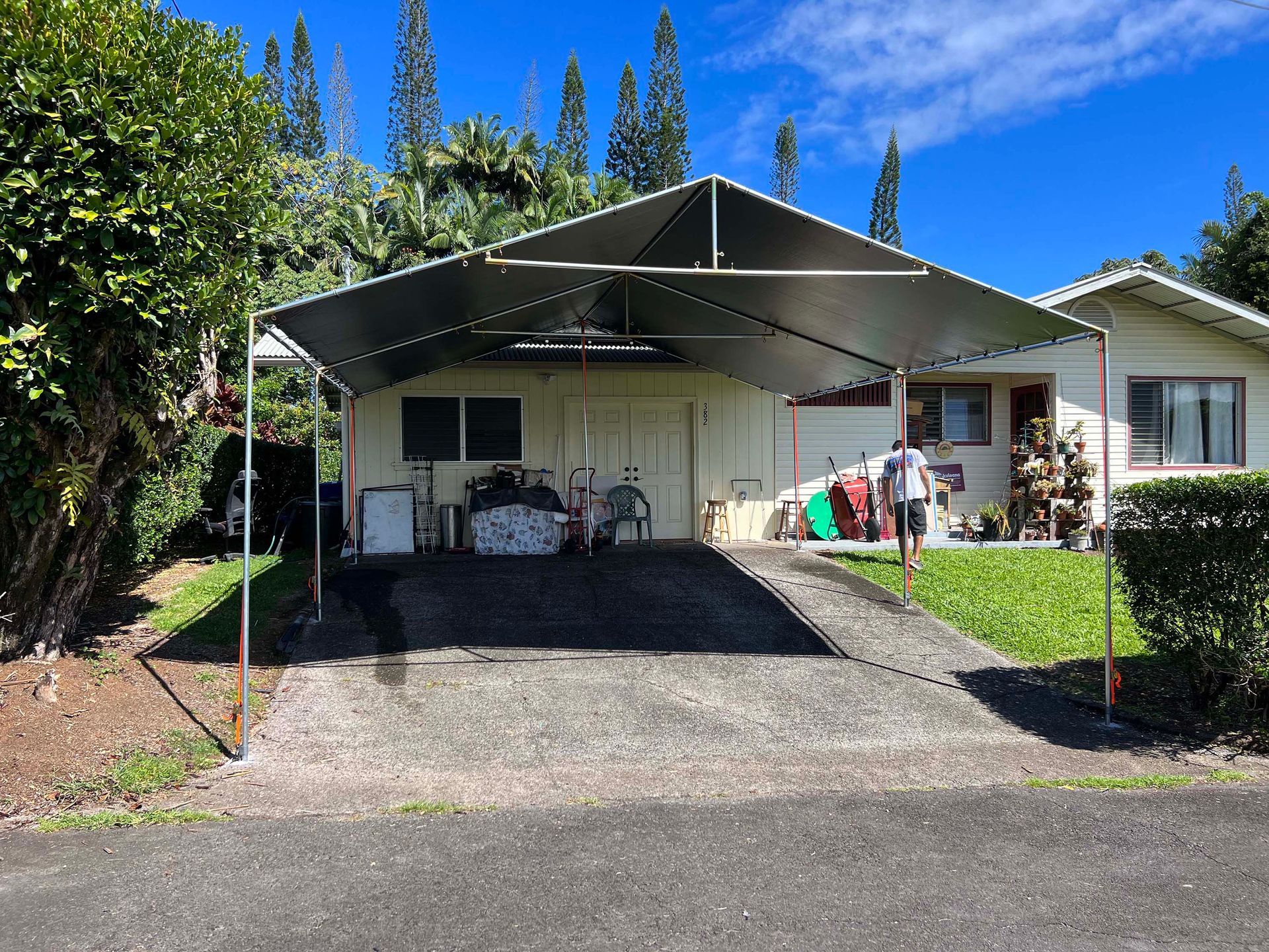 A man is standing in front of a house with a carport.