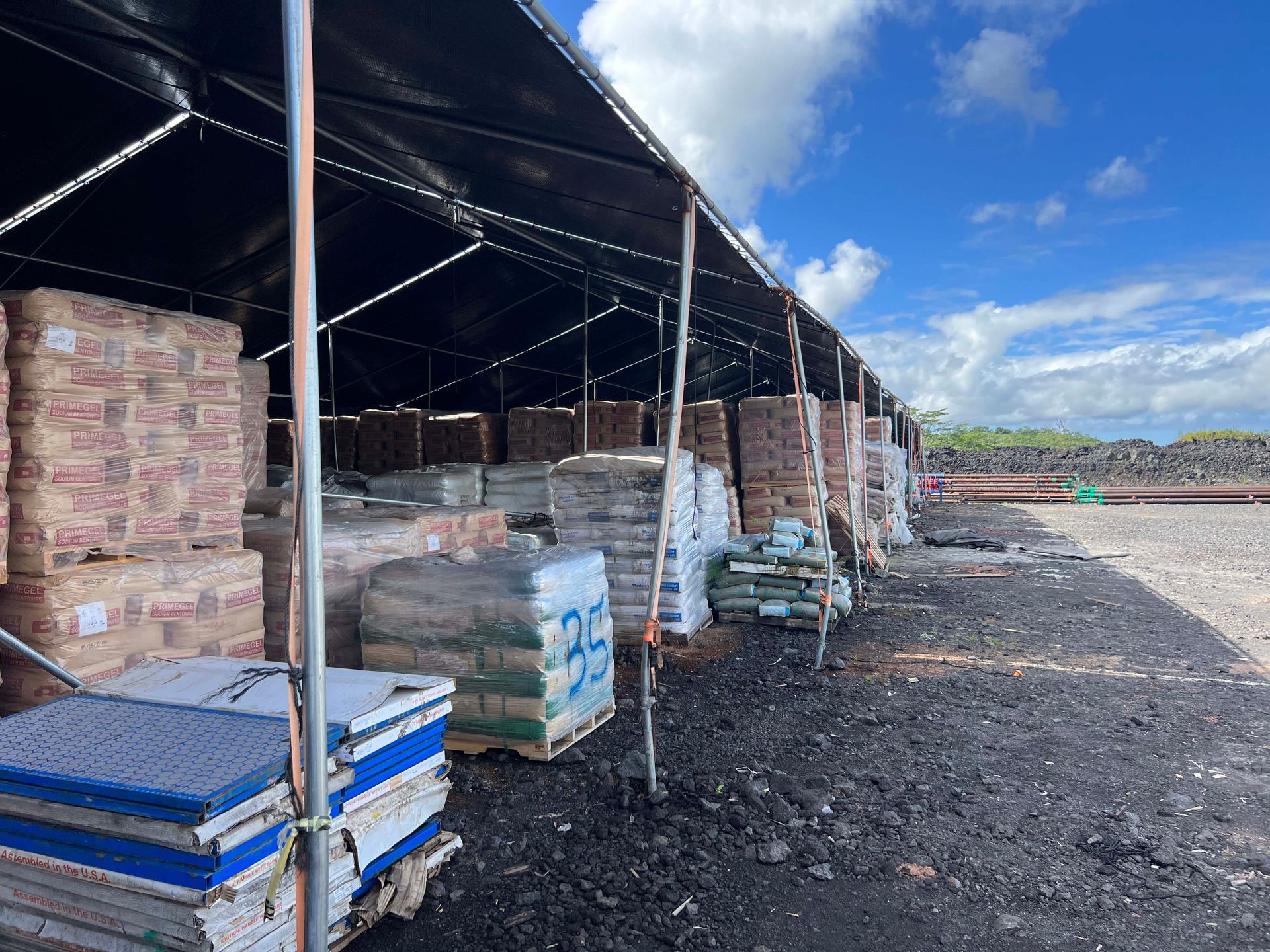 A warehouse filled with lots of boxes and bags under a tent.