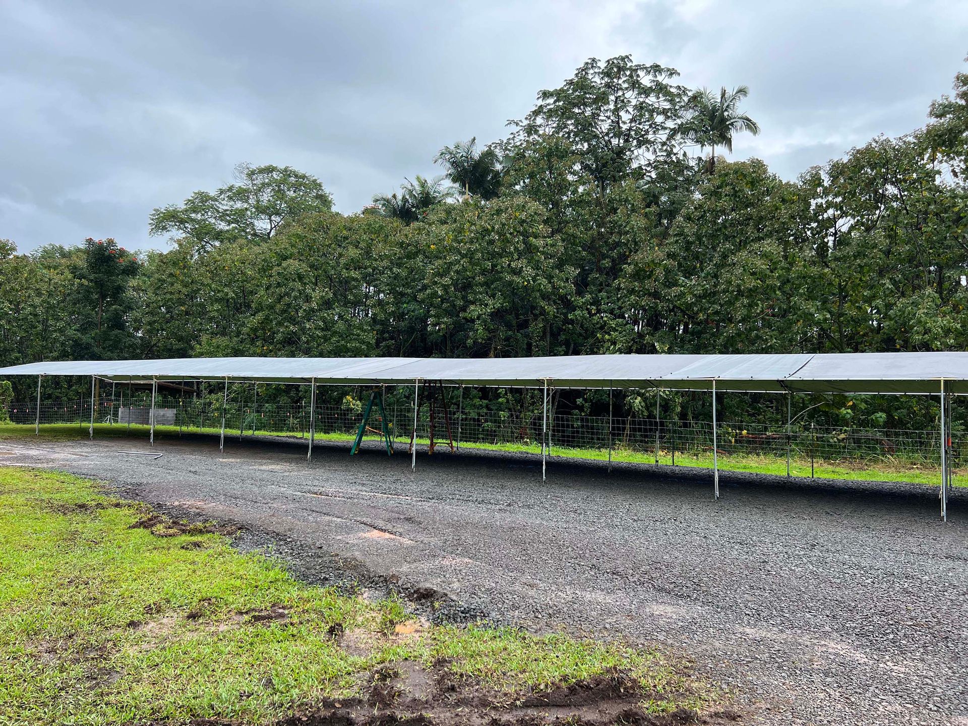 A row of solar panels are sitting on top of a gravel road.
