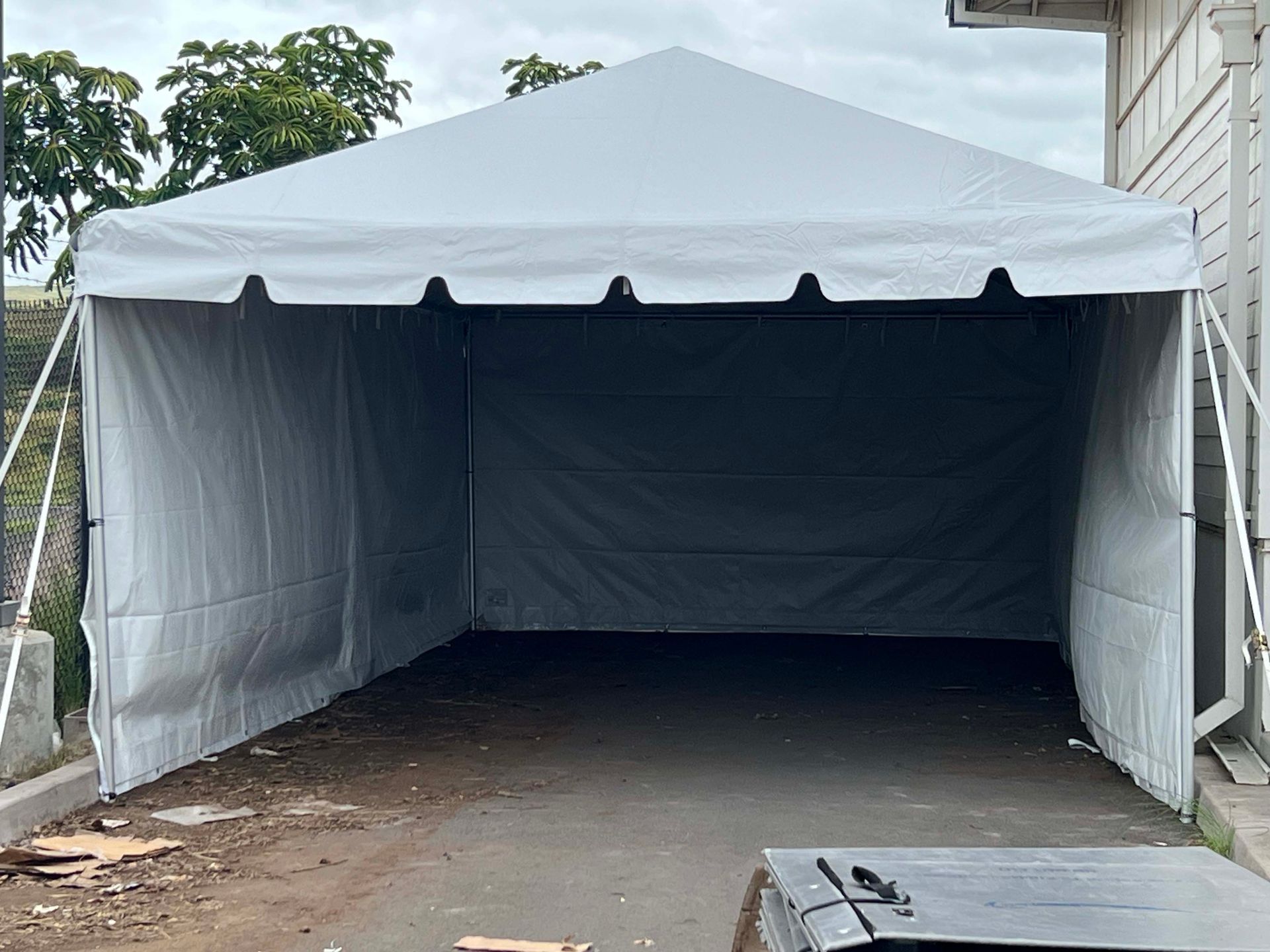 A white tent is sitting in a parking lot next to a building.