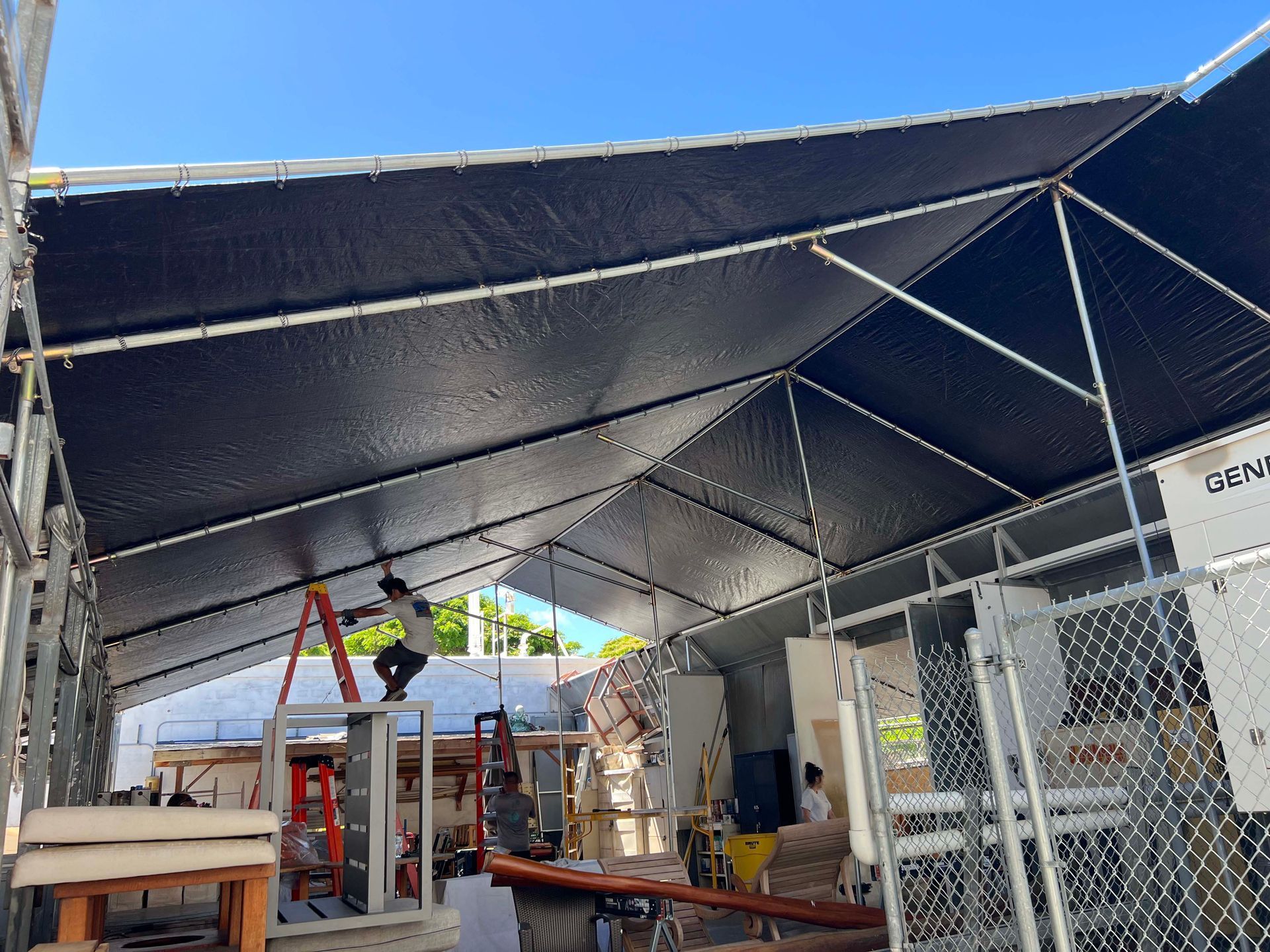 A man is standing on a ladder under a tent.