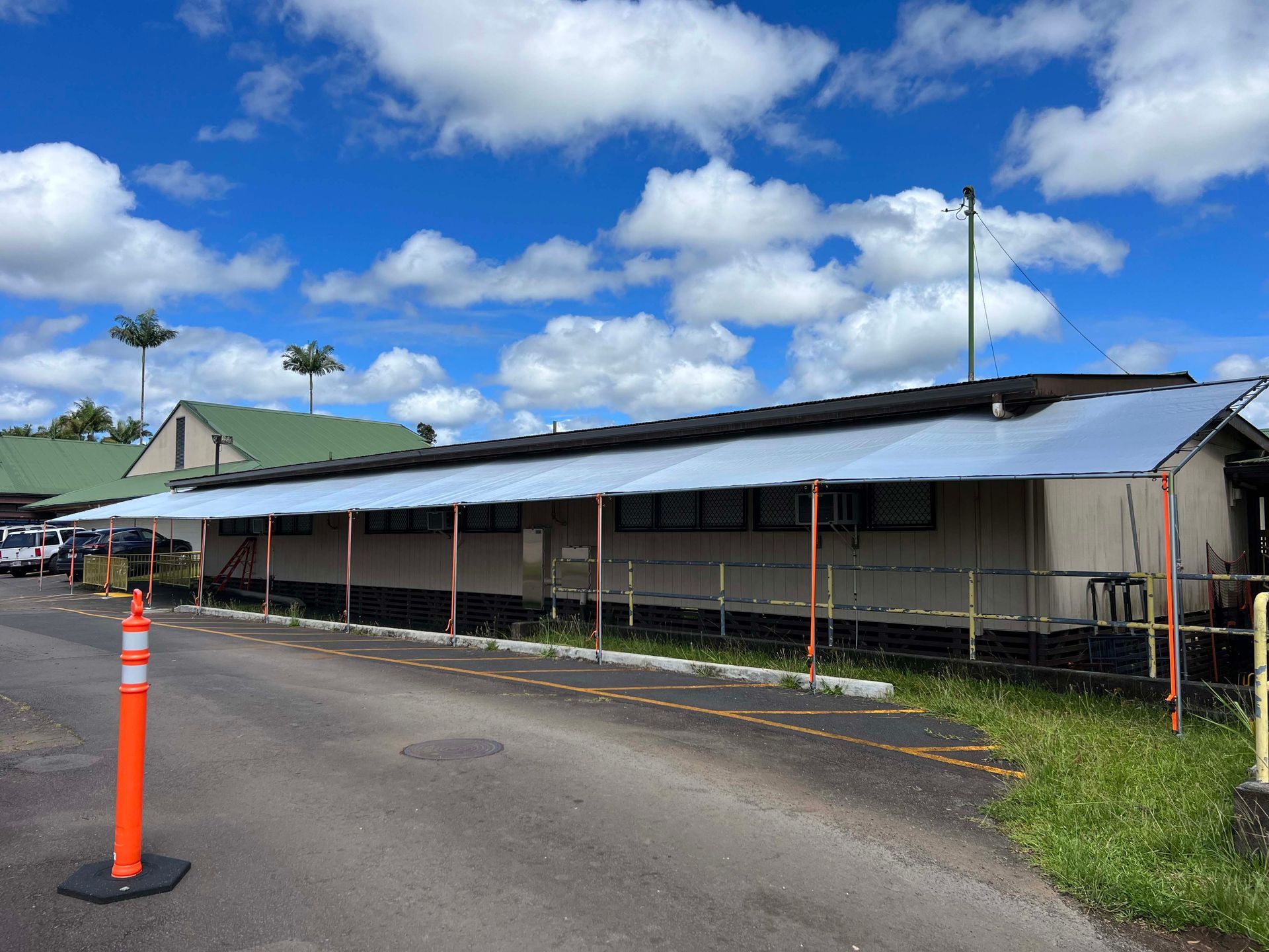 A building with a canopy over it is sitting on the side of a road.