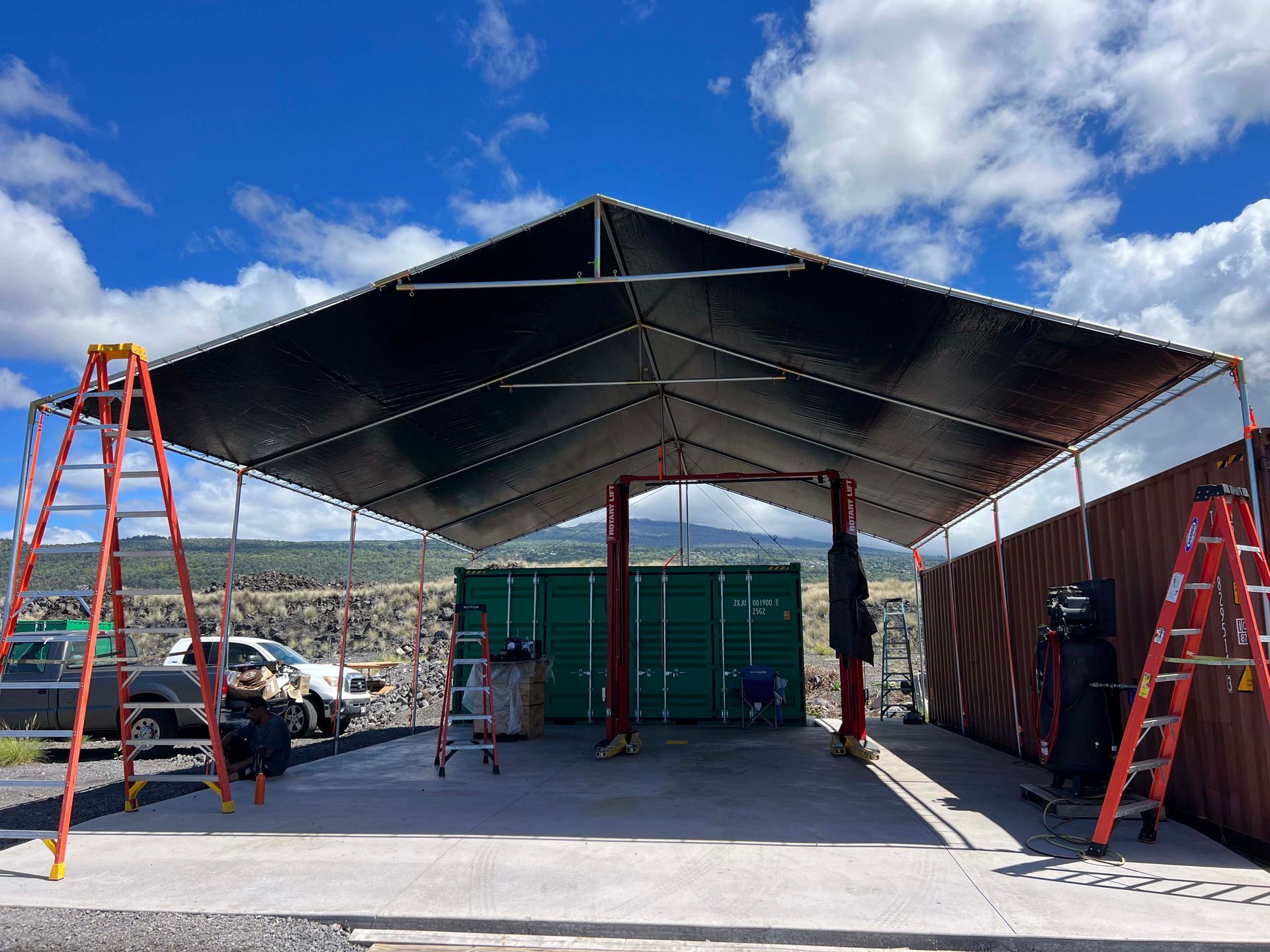 A large tent is being built in a parking lot with ladders.