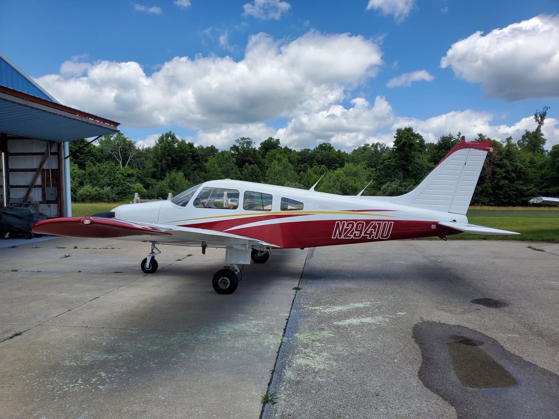 a small yellow airplane with a red nose is on a runway