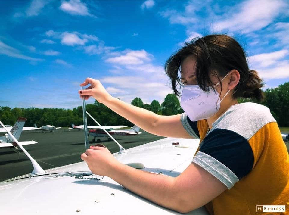 a woman wearing a mask is working on a plane