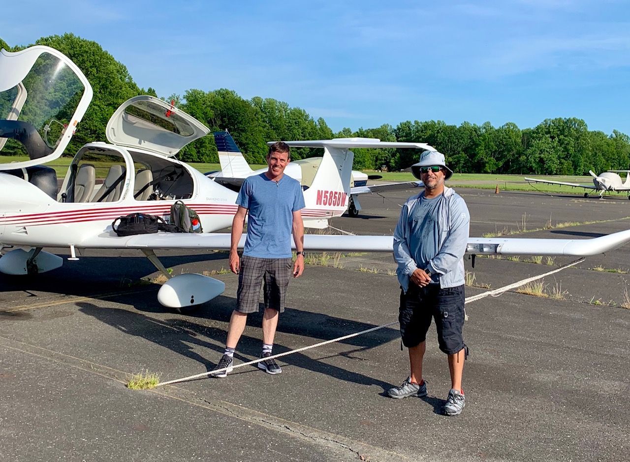 two men are standing in front of a small plane with the door open