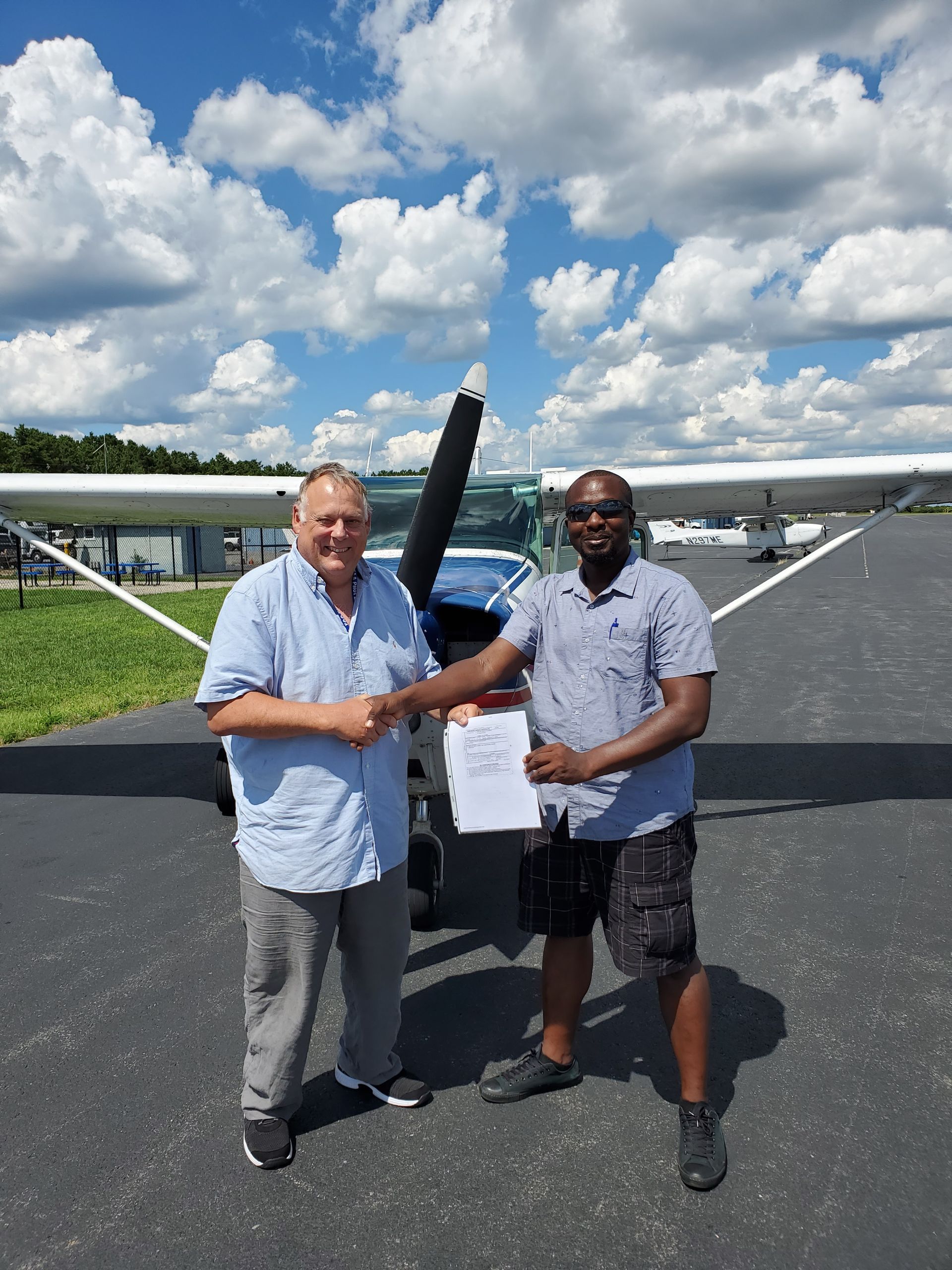 two men shaking hands in front of a small plane