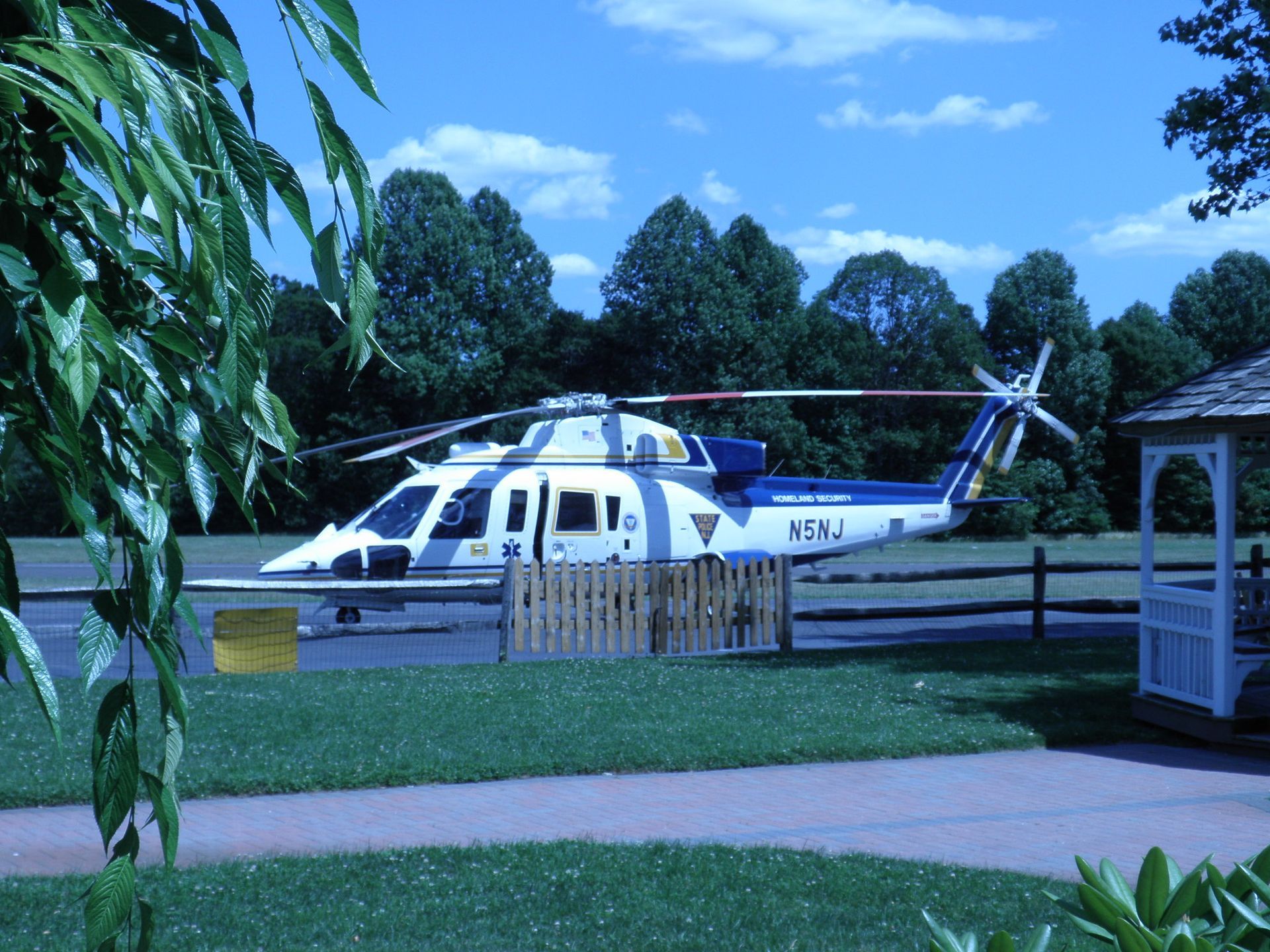 a helicopter is parked in a grassy area with a gazebo in the background
