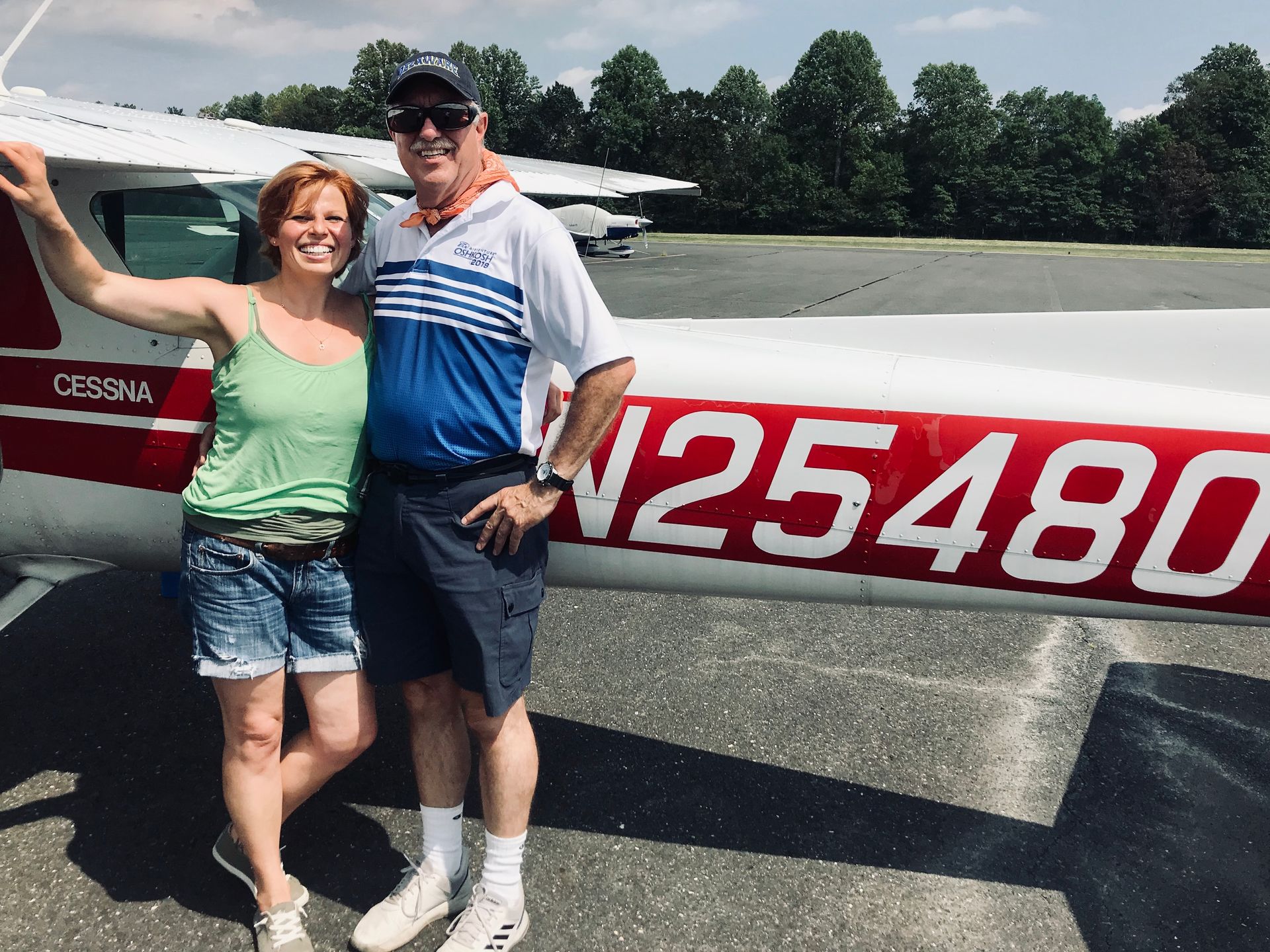 a man and a woman standing in front of a plane with n25480 on the side