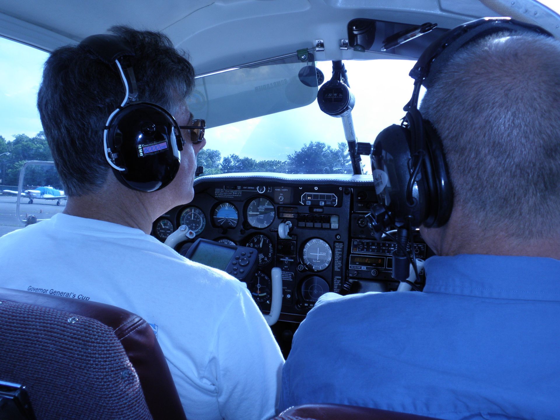 two men wearing headphones are sitting in the cockpit of an airplane