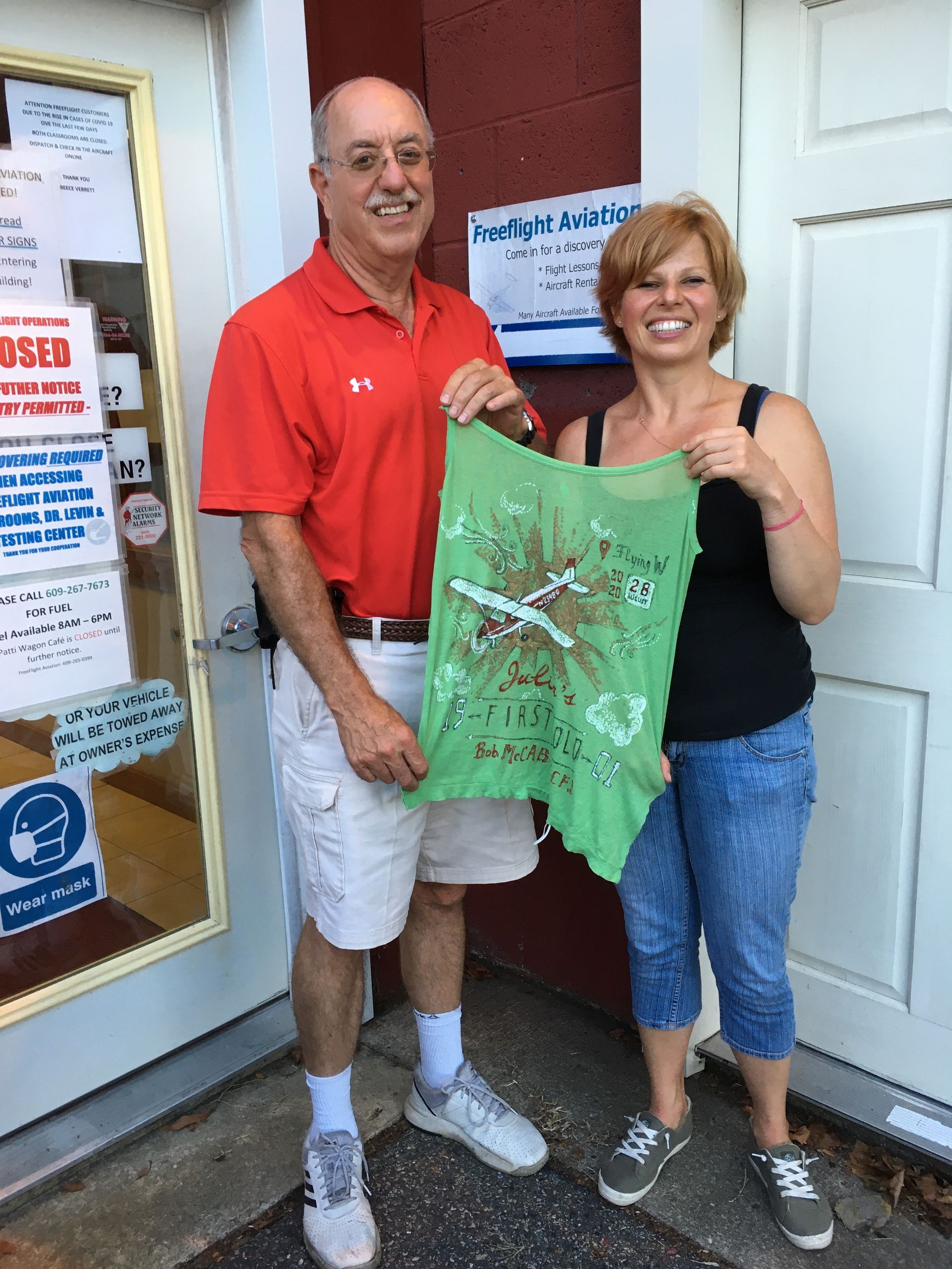 a man and a woman are standing in front of a door holding a green shirt
