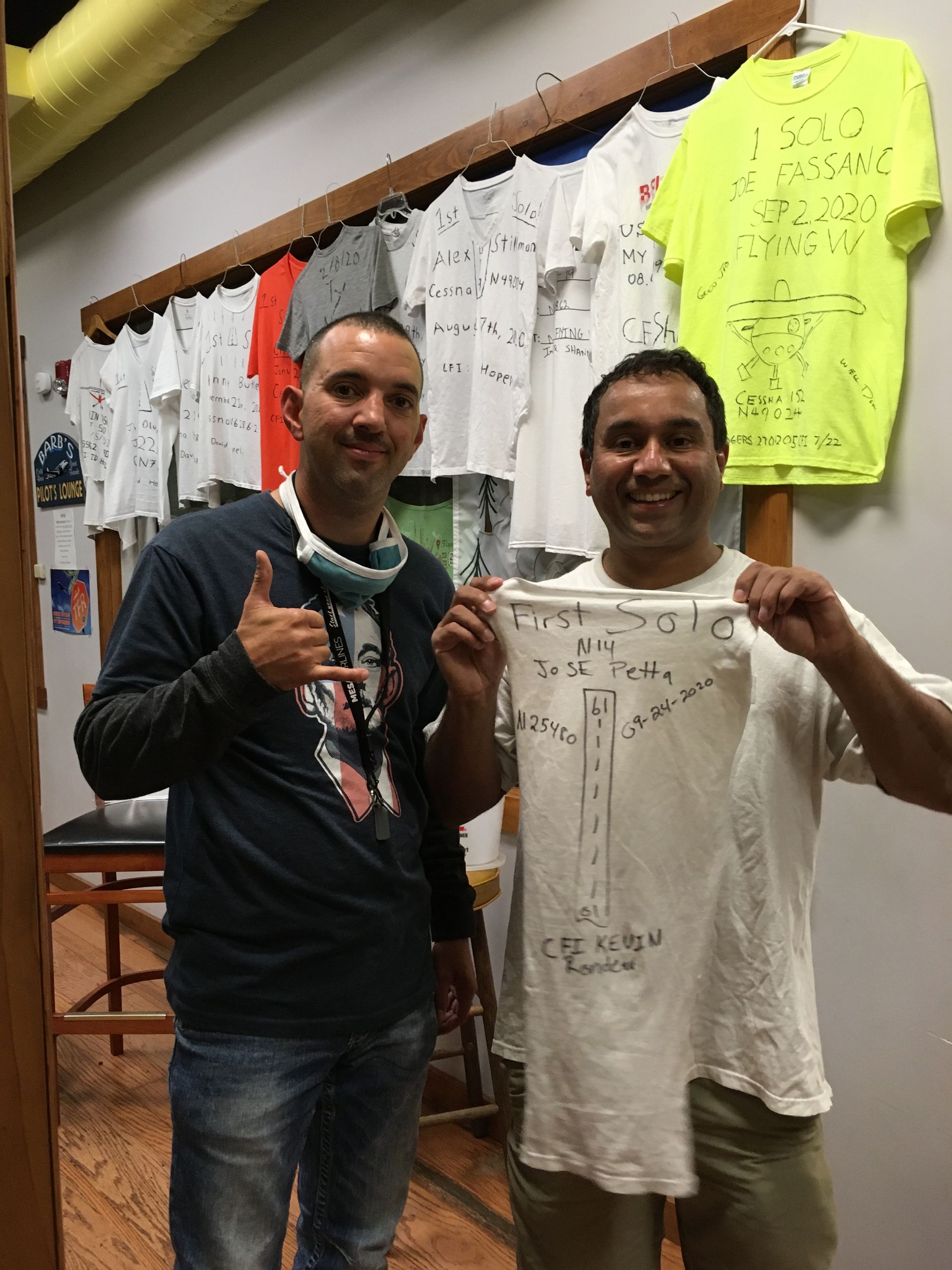 two men are standing next to each other holding a t-shirt with a cross on it