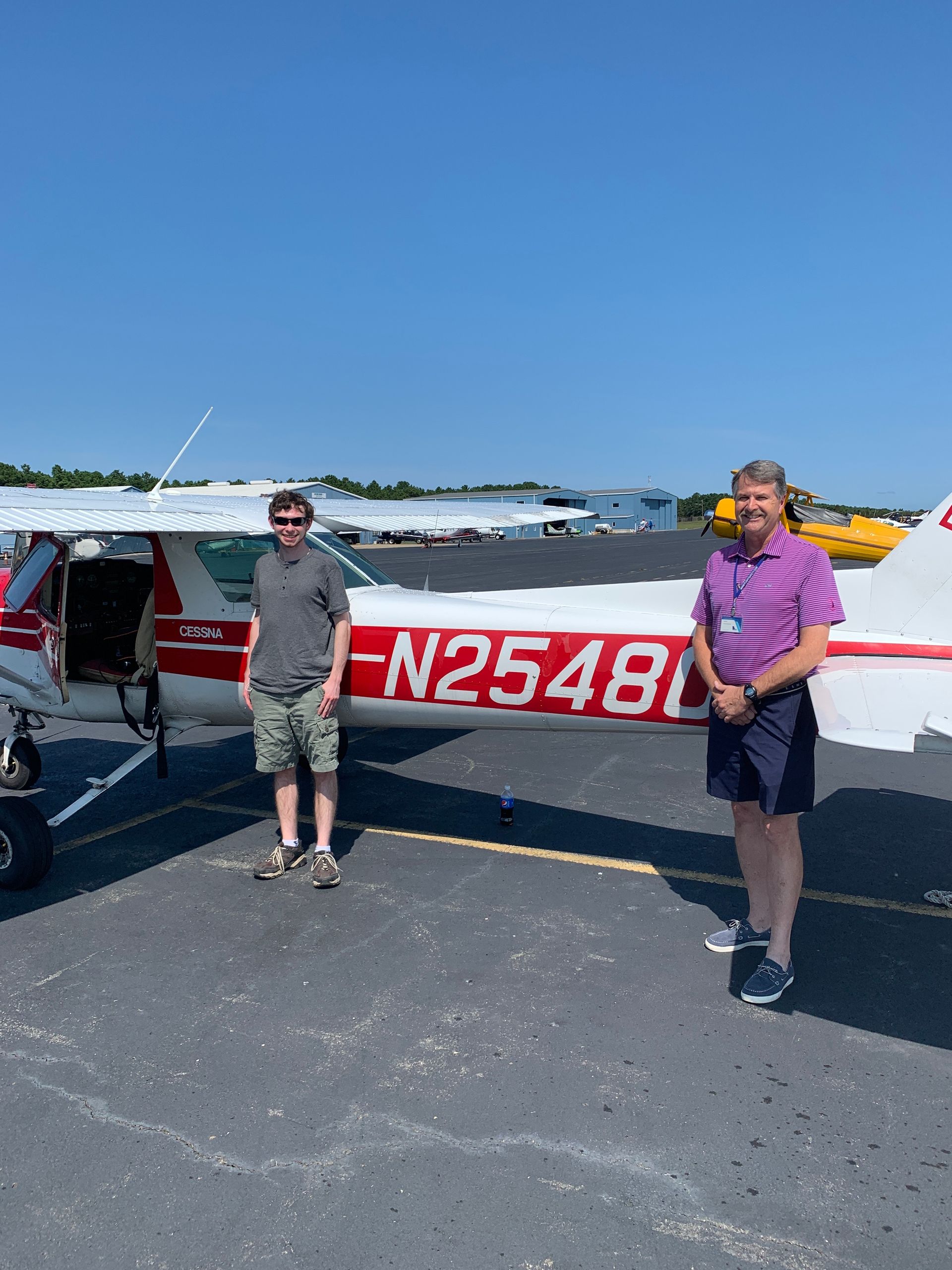 two men are standing in front of a small plane with n2548 on the side