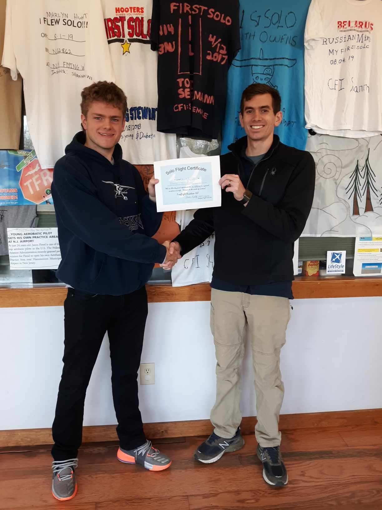 two men shaking hands in front of a sign that says first solo