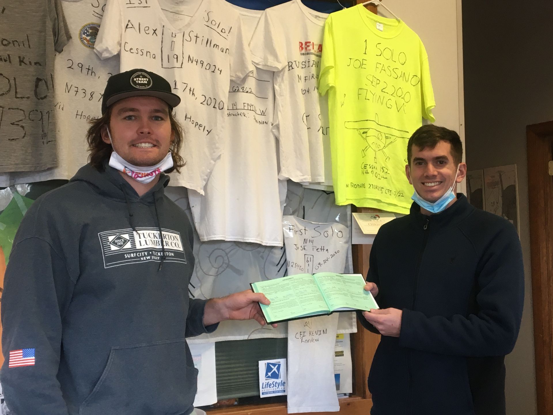 two men are standing in front of a wall with shirts hanging on it