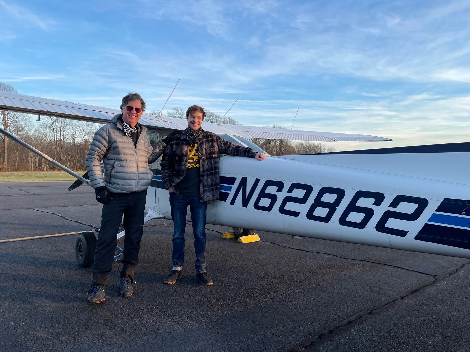 two men are standing in front of a small plane